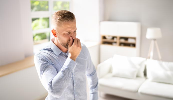 Man pinning nose for bad odor in living room Man pinning nose for bad odor in living room